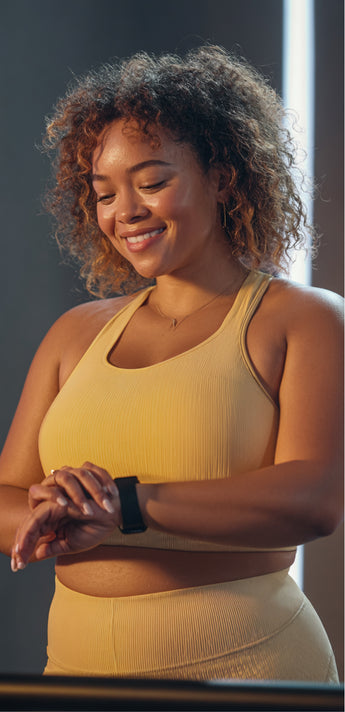 Woman in yellow activewear checking a smartwatch