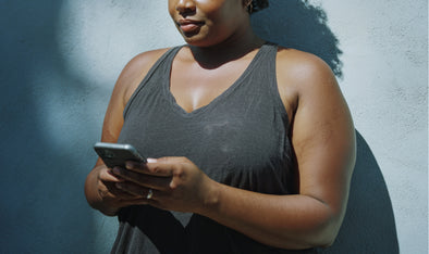 Woman in a tank top using her phone outdoors