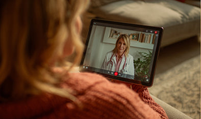 Woman on a tablet video call with a clinician in a white coat